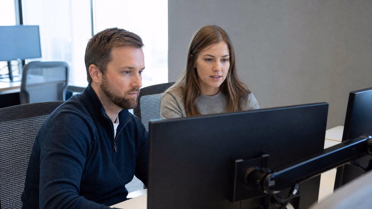 SIDE-BY-SIDE PAIR An IT professional two people seated side by side reviewin